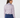 A woman shown from the back wearing a long-sleeve button-up shirt with a small geometric pattern in pink, white, and blue, paired with navy blue trousers.