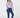 A woman modeling a long-sleeve mock-neck top with a light purple and white geometric pattern, paired with navy blue pants.