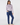A woman modeling a long-sleeve mock-neck top with a light purple and white geometric pattern, paired with navy blue pants.