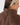 Close-up of a woman wearing a brown sherpa fleece jacket with a high collar and a patterned headband, shown from the side.