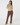 A woman modeling a beige and brown geometric patterned mock-neck long-sleeve top paired with brown trousers and patterned socks.