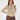 A smiling model wearing a long-sleeve mock neck top with a dense geometric pattern in beige, brown, and yellow, paired with brown pants, against a light gray studio background.