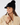 Black women’s ribbed golf beanie with visor, pom-pom and circular star logo, shown on a model.