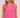 Woman wearing a sleeveless pink top with a small white polka dot pattern and a white decorative trim along the split neckline.