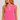 Woman wearing a sleeveless pink top with a small white polka dot pattern and a white decorative trim along the split neckline.