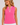 Woman wearing a sleeveless pink top with a small white polka dot pattern and a white decorative trim along the split neckline.