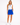 A woman modeling a sleeveless golf white mesh top and a royal blue skirt, featuring blue and white trim details, paired with white sneakers.