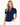 A woman wearing a navy blue short-sleeve golf polo shirt with a white polka dot pattern and white trim along the split neckline and sleeve cuffs, paired with white pants.