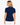 A woman shown from the back wearing a navy blue short-sleeve golf polo shirt with a white micro-dot pattern and white trim on the collar and sleeve cuffs, paired with white pants.