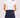 A woman shown from the back wearing a navy blue A-line golf skort with white decorative trim and a small embroidered star paired with a white short-sleeve ruffled blouse.