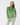 A woman modeling a green long-sleeve quarter-zip athletic top with a matching green and white patterned headband and matching patterned leggings.